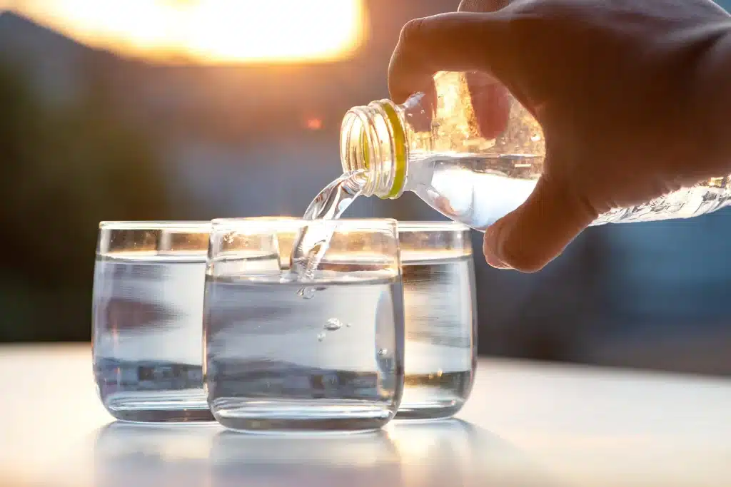 man pouring several glasses of water